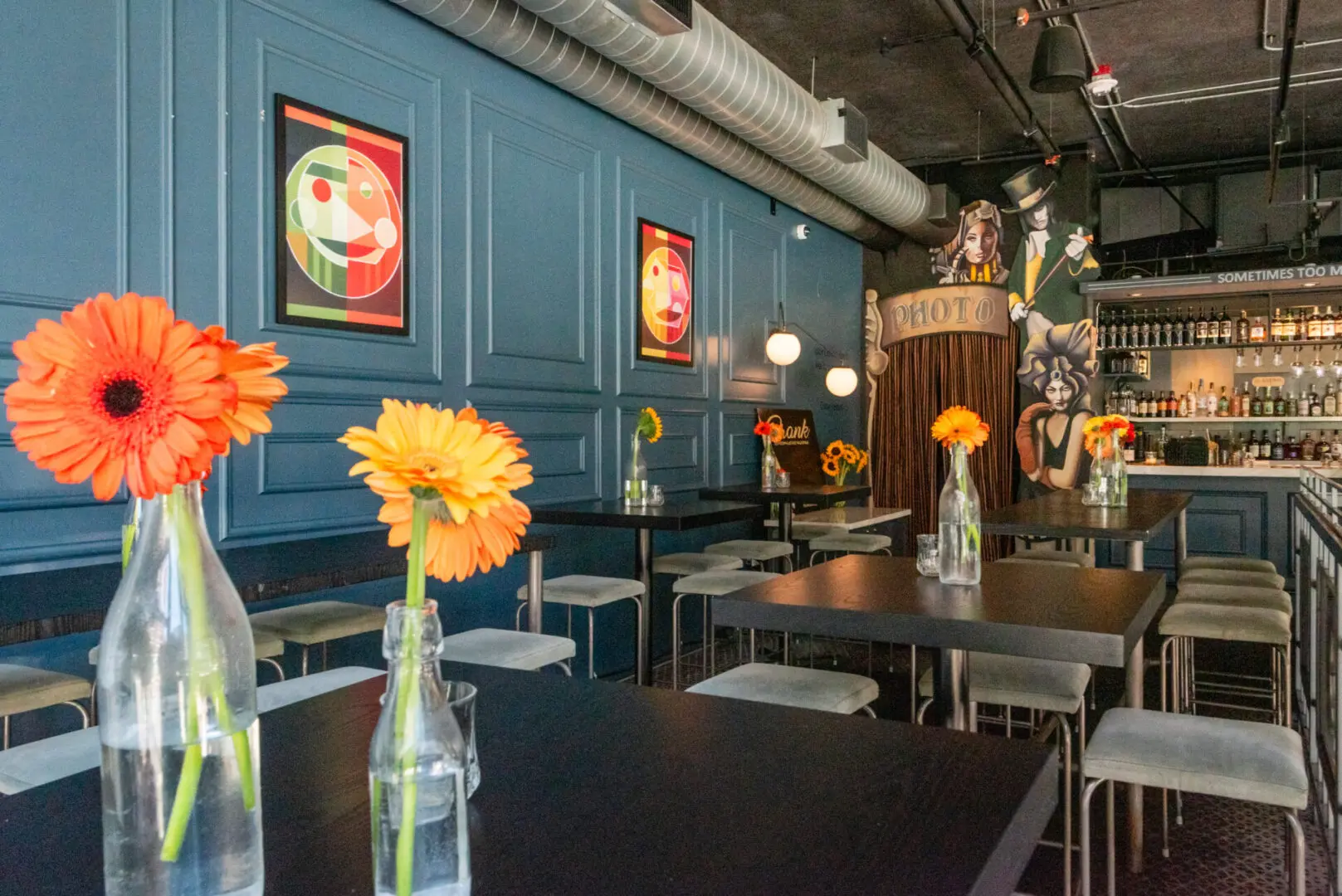 A restaurant with tables and chairs, flowers in vases on the table.