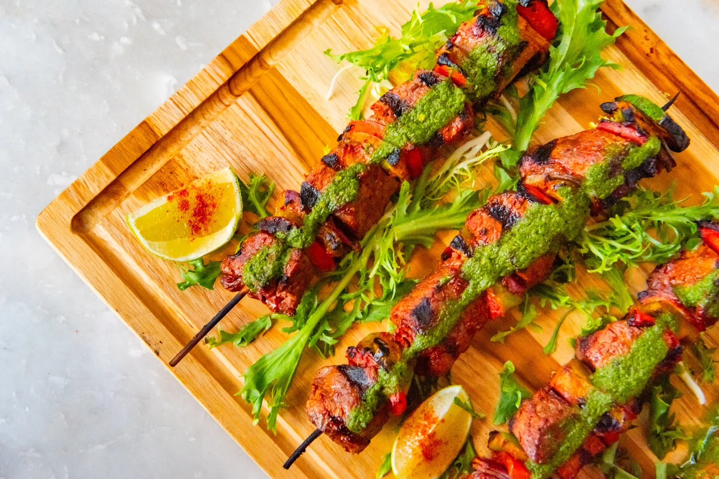 A wooden cutting board topped with meat and vegetables.