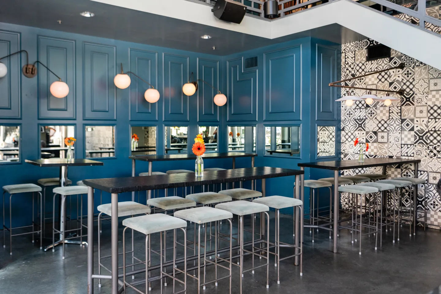 A bar with blue walls and white stools.